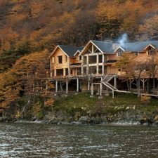 Lodge on the side of a hill, surrounded by autumn forests, steps from the river.