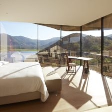 Room with double bed and large windows overlooking the lagoon and hills.