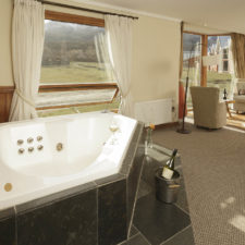Spacious hotel room with Jacuzzi included, living room and view of the surroundings.