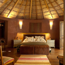 Circular style bungalow with double bed and rustic furniture.