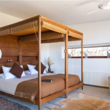 Interior view of room with double canopy bed, simple and neat decoration.