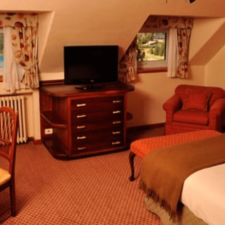Room interior with double bed, desk and seat for rest. Room with heating and TV, overlooking the lake.