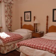Interior view of room with two single beds. Window overlooking gardens.