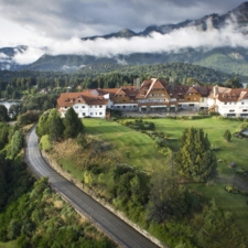 Beautiful panoramic view of the hotel on top of a gentle hill, surrounded by forest lakes.