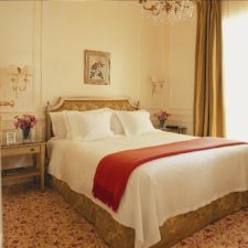 Room with single bed. Elegant rugs and classic design. The light filters through a large window.
