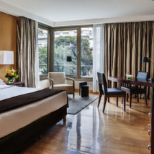 Luxurious hotel room with a double bed, beautiful wooden floors and a window with a view of the city.