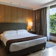 Luxurious hotel room with a double bed, beautiful wooden floors and a window with a view of the city.