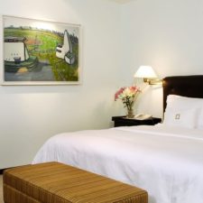 Hotel room with double bed with small desk included. Bright room with brightly colored paintings.