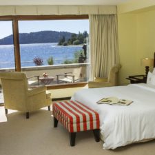 Hotel room with double bed, TV, two seats and central table to enjoy a beautiful view of the lake. The room has a private terrace and a lake view