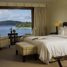 Hotel room with double bed, two seats and central table to enjoy a beautiful view of the lake.