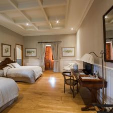 Interior view of room with two double beds, wooden floors and high ceilings. Mix of modern and classic.