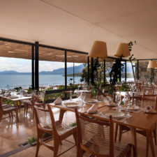 View of the dining room with large windows overlooking the terrace and sea.