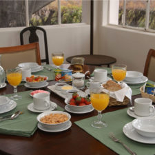 Cozy table set with four breakfast stands. Juices, cereals, fresh fruits. Simple and cozy.