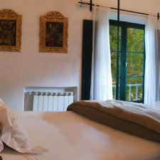 Room with double bed and colonial decoration. Large window overlooking the environment.