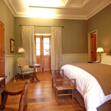 Interior view of room with double beds, wooden floors and high ceilings. Mix of modern and classic.