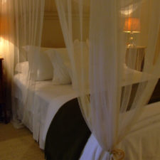 Room with double bed with white fabric canopy.