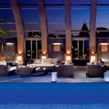 View of the indoor pool with living rooms on the terrace. Glass dome with curved wooden beams. Panoramic view of the city.