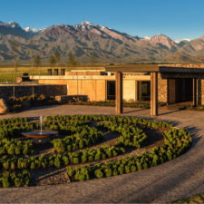 Main entrance to a restaurant in the management house of a vineyard. Stone path with adjacent gardens designed for walking. In the background you see a mountain range.