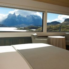 Interior view of a room with a double bed, a living room and a beautiful view of the Torres del Paine.