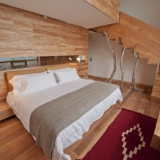 View of room on two floors with double bed and beautiful native wood architecture.