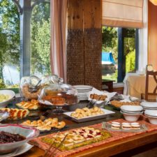Buffet table with delicious characteristic Argentine pastry. Wide variety of flavors and beautiful visual variety. Architecture with worked wood and direct view of the lake.