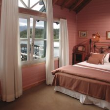 Interior view of a room with a double bed and windows overlooking the lake a few meters away.