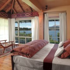 Interior view of room with double bed, indoor lounge chair to enjoy the lake view. Direct access to outside terrace.